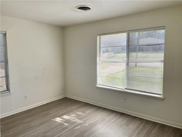 unfurnished room with baseboards, plenty of natural light, and wood finished floors