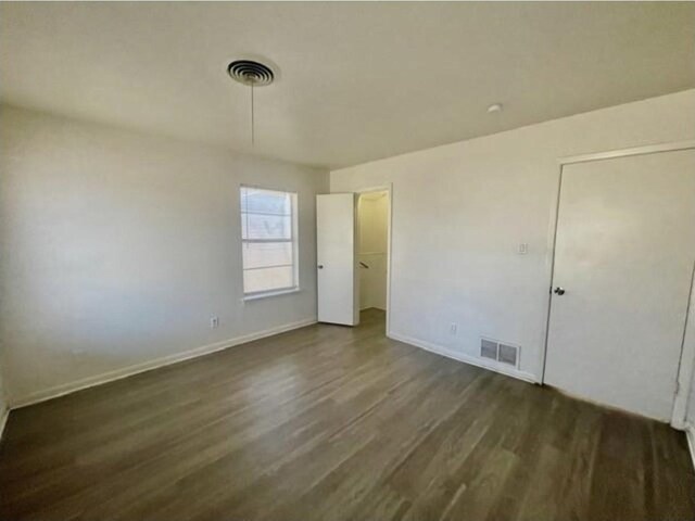 unfurnished bedroom featuring baseboards, visible vents, and wood finished floors