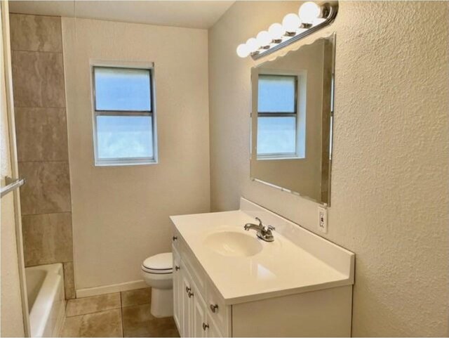 bathroom with vanity, a textured wall, tile patterned floors, and toilet