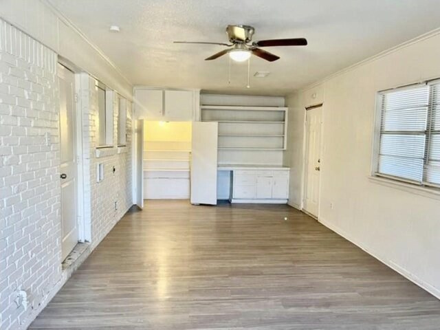 unfurnished living room featuring crown molding, ceiling fan, and wood finished floors