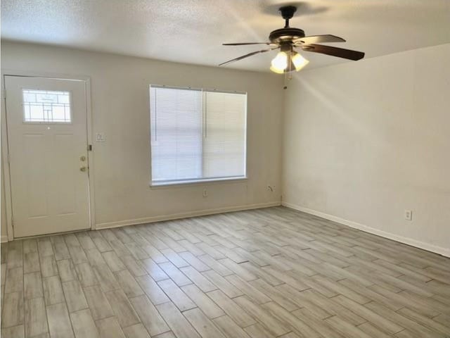 foyer entrance featuring baseboards, ceiling fan, and light wood-type flooring