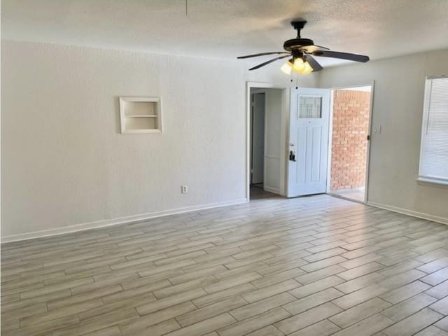 unfurnished room featuring a ceiling fan, baseboards, and light wood finished floors