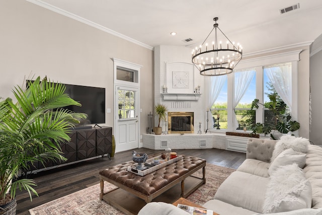 living area with visible vents, crown molding, a brick fireplace, dark wood-style floors, and a notable chandelier