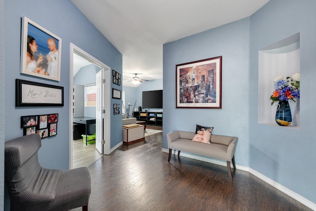 living area featuring dark wood-type flooring, a ceiling fan, and baseboards