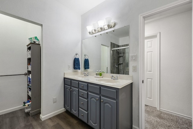 full bath featuring double vanity, a shower stall, a sink, and wood finished floors