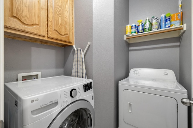 washroom featuring cabinet space, separate washer and dryer, and a textured wall