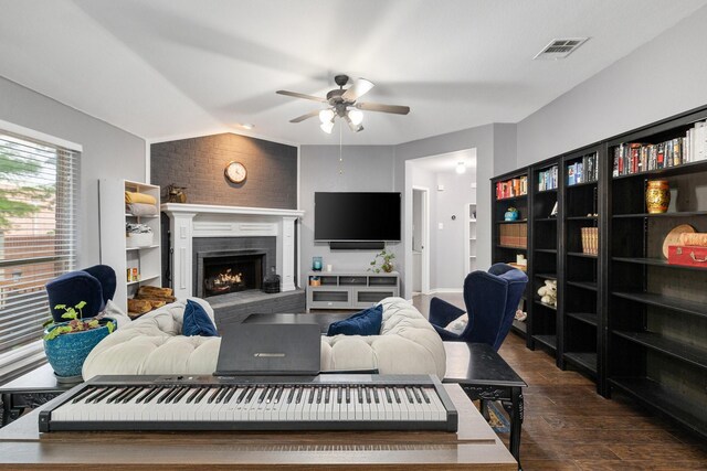 living room with ceiling fan, a lit fireplace, dark wood-style flooring, and visible vents