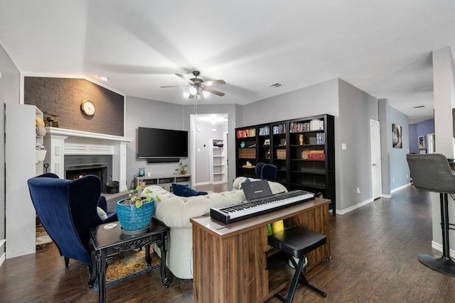 living room with a warm lit fireplace, ceiling fan, dark wood-style floors, and baseboards