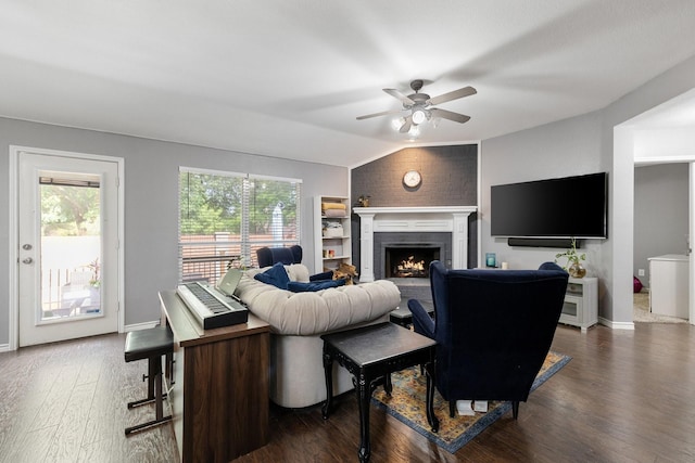 living area featuring dark wood-type flooring, a ceiling fan, a wealth of natural light, and a fireplace