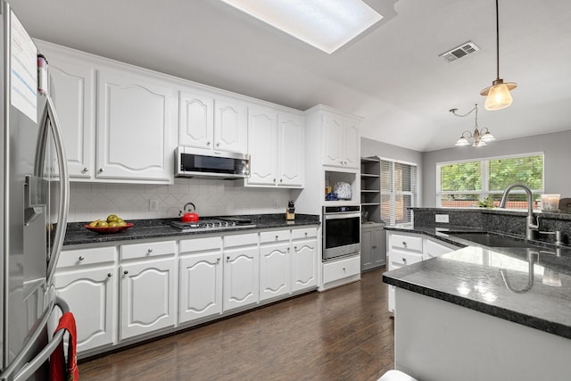 kitchen with white cabinets, a sink, stainless steel appliances, decorative backsplash, and visible vents