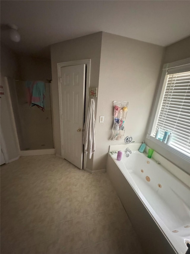 bathroom featuring a tub with jets, baseboards, and a stall shower