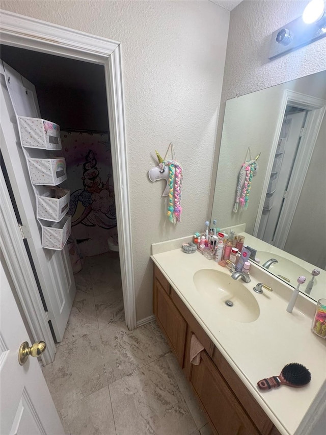 bathroom featuring vanity, marble finish floor, and a textured wall