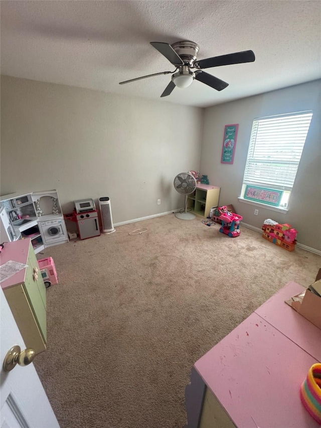 recreation room featuring carpet floors, ceiling fan, baseboards, and a textured ceiling