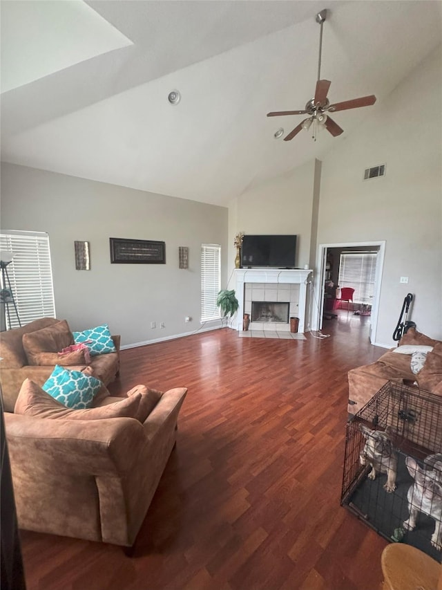 living room with a ceiling fan, high vaulted ceiling, wood finished floors, and a tile fireplace