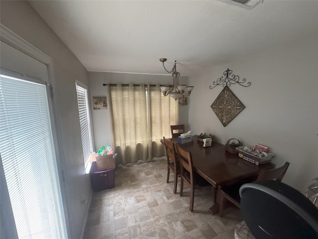 dining area featuring stone finish floor, plenty of natural light, visible vents, and a notable chandelier