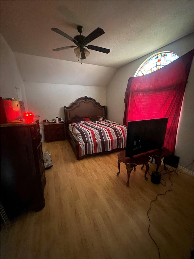bedroom with a ceiling fan, wood finished floors, and lofted ceiling