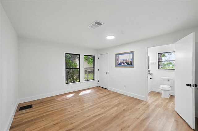 unfurnished bedroom featuring baseboards, visible vents, and multiple windows