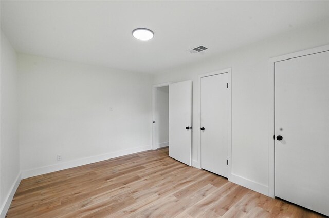 unfurnished bedroom featuring light wood-style floors, baseboards, and visible vents