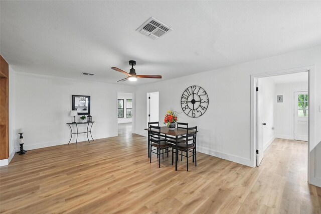 dining area with light wood-style floors, a wealth of natural light, a ceiling fan, and visible vents