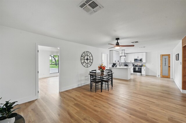 dining room featuring light wood-style floors, baseboards, ceiling fan, and visible vents