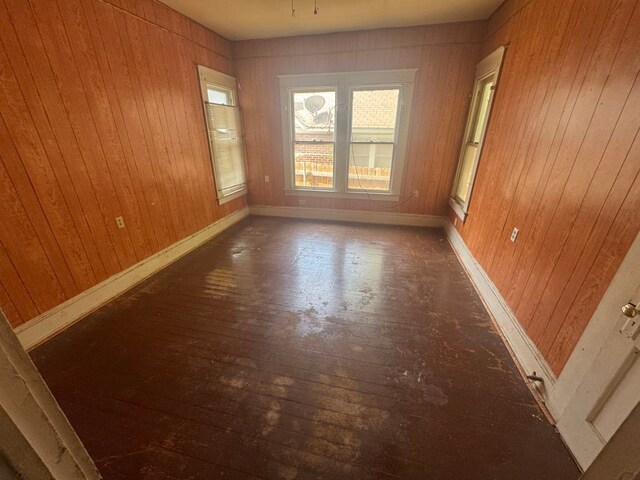 unfurnished room with wooden walls, baseboards, and hardwood / wood-style flooring