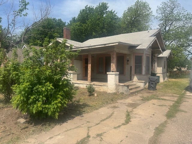 view of front of house featuring covered porch and a chimney