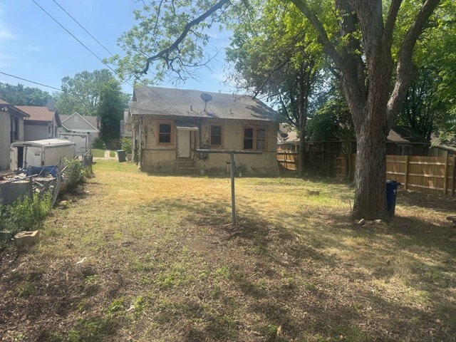 rear view of property with fence and a yard