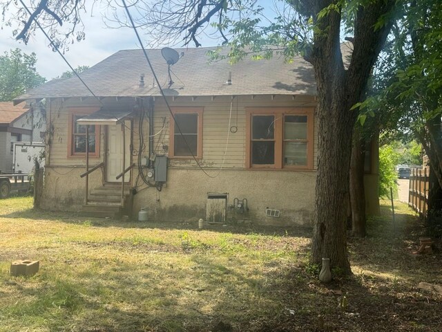 view of front of house featuring roof with shingles, entry steps, and a front lawn