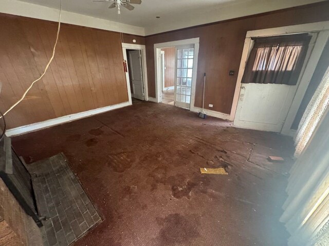 unfurnished room featuring baseboards, a ceiling fan, and wood walls