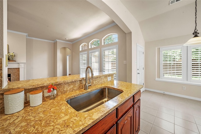 kitchen with arched walkways, light stone counters, a healthy amount of sunlight, and a sink
