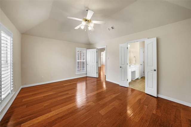 unfurnished bedroom with ceiling fan, visible vents, vaulted ceiling, baseboards, and hardwood / wood-style floors