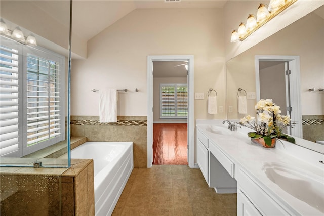 bathroom with double vanity, plenty of natural light, tile patterned flooring, and a garden tub