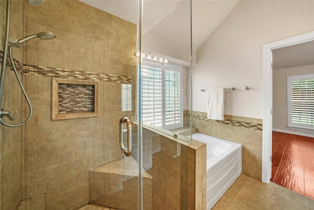 bathroom featuring tile patterned flooring, tile walls, a bath, a stall shower, and vaulted ceiling