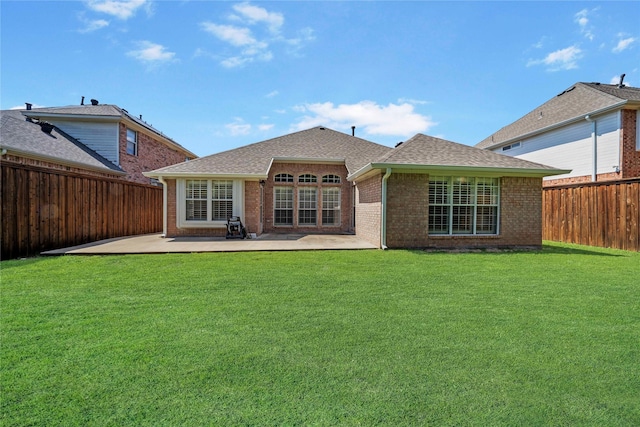 back of house with brick siding, a fenced backyard, a patio area, and a yard