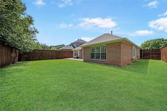 back of house featuring a yard, brick siding, a shingled roof, and a fenced backyard