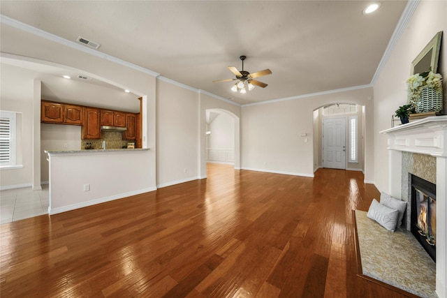 unfurnished living room with arched walkways, a ceiling fan, visible vents, and light wood-type flooring