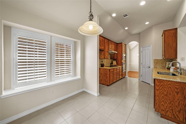 kitchen with a sink, arched walkways, stainless steel oven, tasteful backsplash, and visible vents