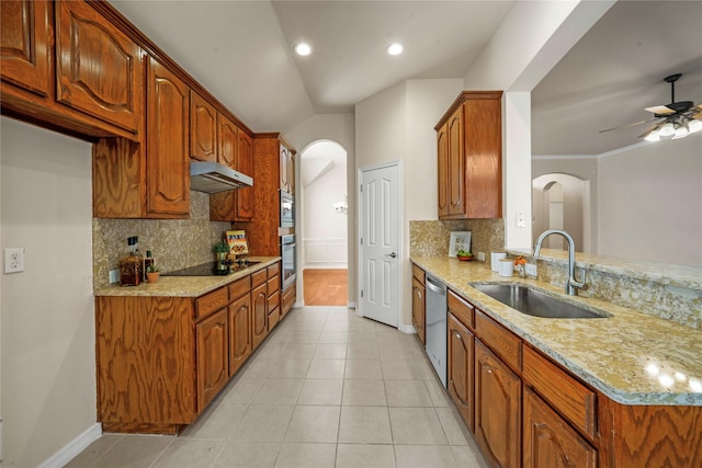 kitchen featuring arched walkways, a sink, light stone countertops, and stainless steel appliances