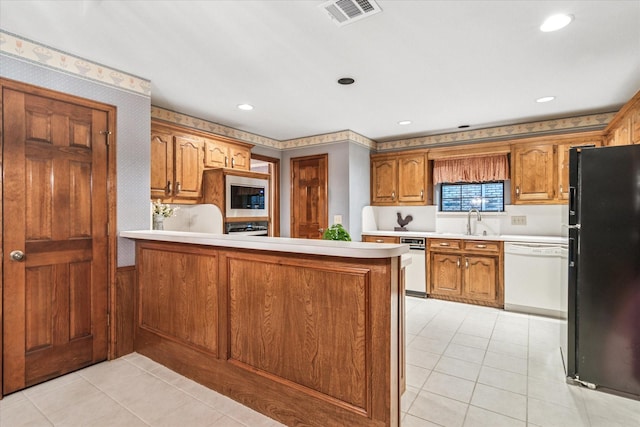 kitchen with visible vents, freestanding refrigerator, a peninsula, light tile patterned floors, and dishwasher