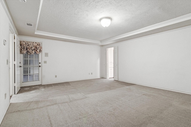 empty room with crown molding, a tray ceiling, carpet flooring, and visible vents