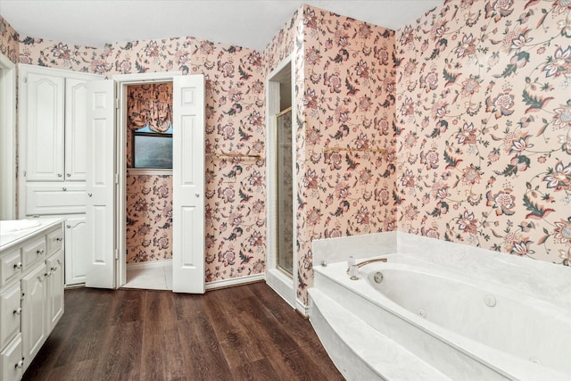 bathroom featuring wallpapered walls, a shower stall, wood finished floors, and vanity
