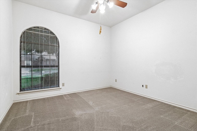 carpeted spare room with baseboards and a ceiling fan