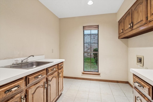 clothes washing area featuring a sink, washer hookup, baseboards, and cabinet space