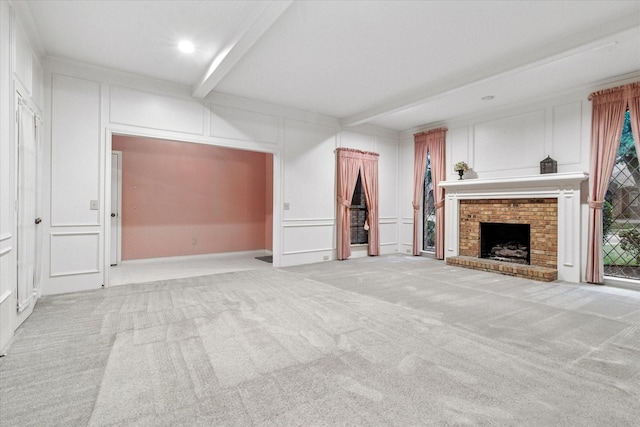 unfurnished living room featuring a fireplace, beamed ceiling, light carpet, and a decorative wall