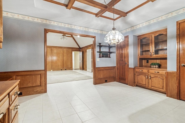 unfurnished dining area featuring beamed ceiling, wallpapered walls, a wainscoted wall, and coffered ceiling