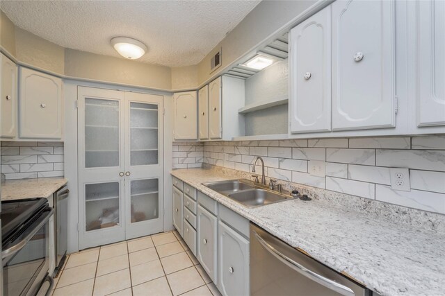 kitchen with backsplash, a textured ceiling, visible vents, appliances with stainless steel finishes, and a sink
