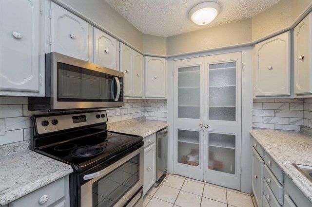 kitchen featuring light countertops, decorative backsplash, a textured ceiling, and stainless steel appliances