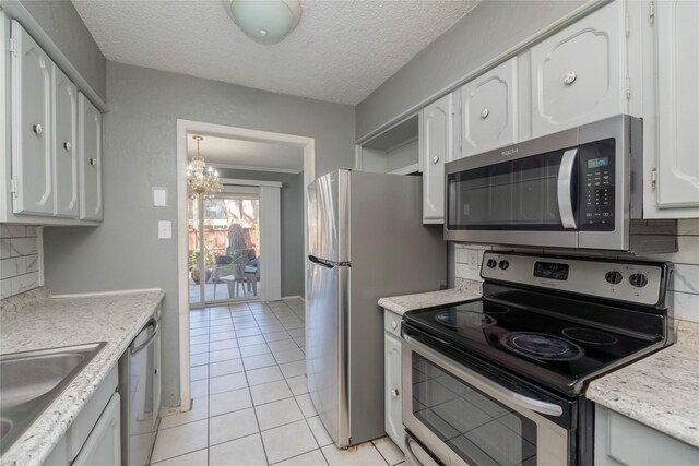 kitchen with appliances with stainless steel finishes, tasteful backsplash, light countertops, white cabinets, and an inviting chandelier