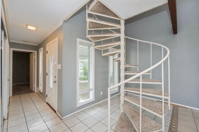 interior space featuring crown molding, a textured ceiling, tile patterned floors, and baseboards