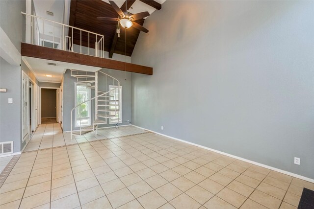 empty room featuring ceiling fan, stairway, high vaulted ceiling, baseboards, and tile patterned floors